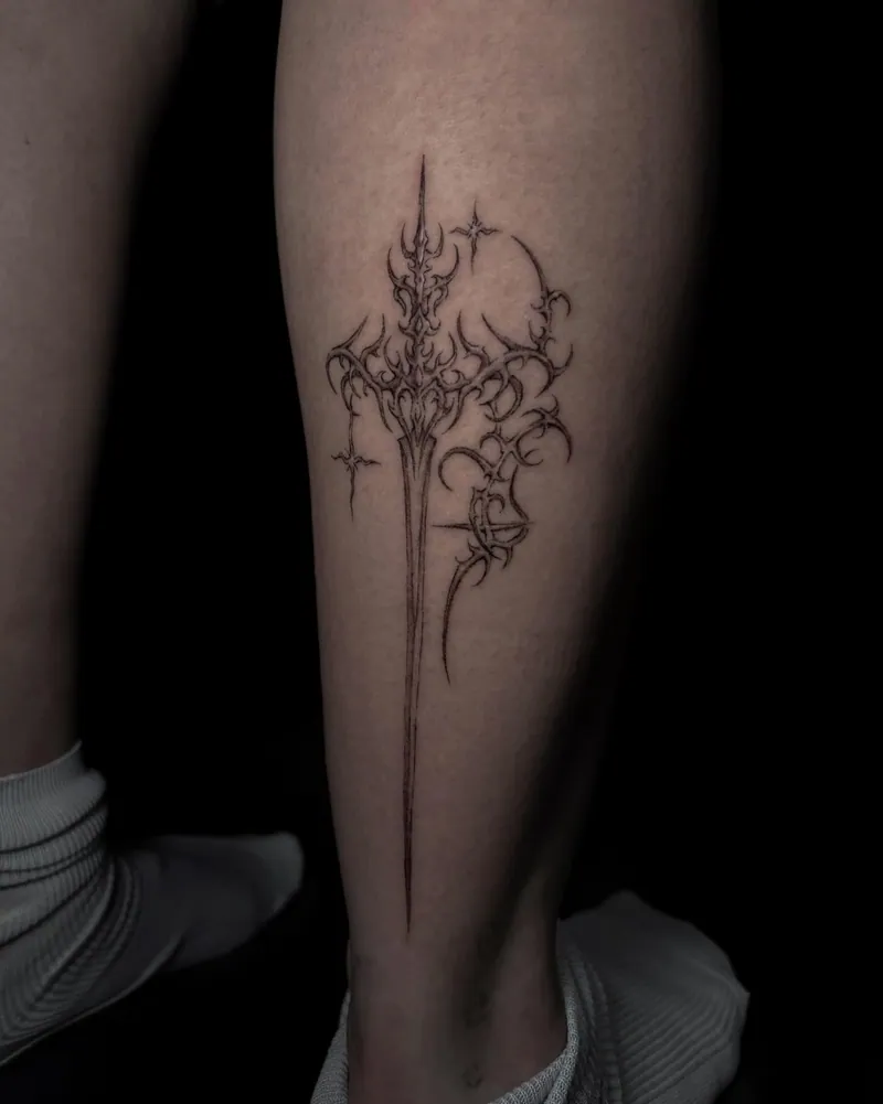 Piccola composizione nera di glifi e punte sulla gamba, dal portfolio di Valentine Tattoo